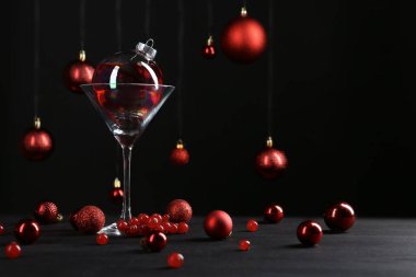 Mücevherlerle süslenmiş Noel kokteylinin yaratıcı sunumu ve siyah masanın üzerindeki cam.