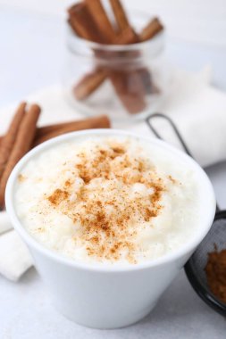 Delicious rice pudding with cinnamon on light table, closeup