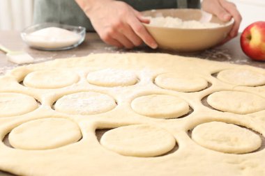 Woman making pirozhki (stuffed pastry pies) at wooden table indoors, closeup clipart