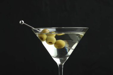 Martini cocktail with olives in glass on black background, closeup clipart