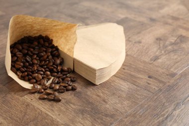 Kağıt filtreler ve kahve çekirdekleri ahşap masada. Metin için boşluk