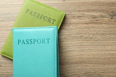 Parlak örtülü iki pasaport, ahşap masa, üst manzara. Metin için boşluk