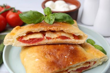 Domatesli, peynirli ve fesleğenli vejetaryen calzone parçaları, yakın plan.