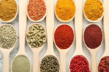 Farklı aromatik baharatlar beyaz mermer masa üzerinde kaşıklar, düz yatıyordu