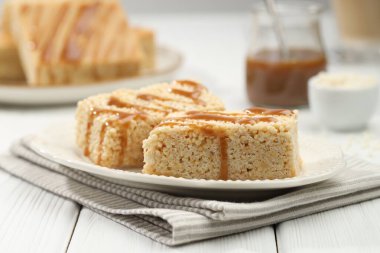 Lezzetli karamelli pirinç çubukları beyaz ahşap masada, yakın plan.