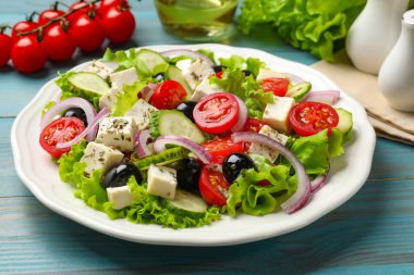 Peynirli leziz salata ve açık mavi ahşap masa malzemeleri, yakın plan.