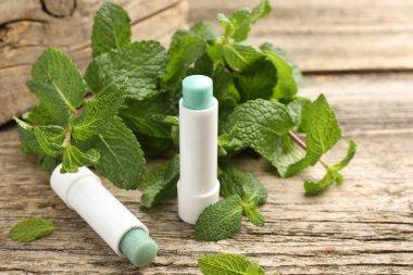 Doğal dudak kremleri ve ahşap arka planda nane yaprakları.