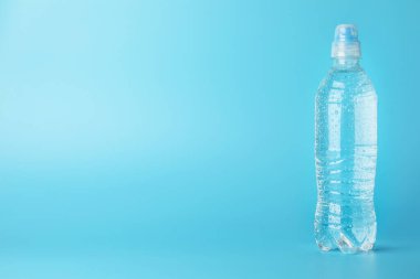 Açık mavi zemin üzerinde plastik su şişesi, metin için boşluk