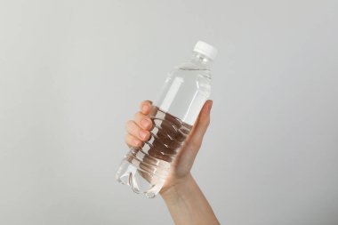 Arka planda plastik su şişesi tutan kadın, yakın plan.