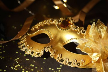 Güzel bir karnaval maskesi, koyu arkaplanda kurdele ve konfeti, yakın plan.