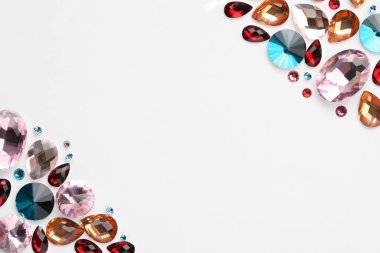 Beyaz arka planda farklı parlak taşlar, düz bir zemin. Metin için boşluk