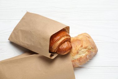 Taze baget ve kruvasan ile beyaz ahşap masa, üst manzara.