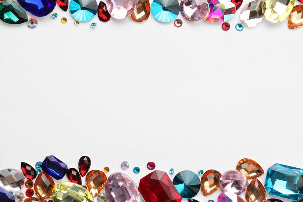 Frame of different shiny gemstones on white background, flat lay. Space for text