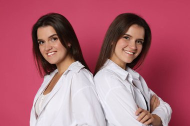 Pembe arka planda güzel ikiz kız kardeşlerin portresi