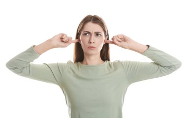 Kadın kulaklarını beyaz arka planda parmaklarıyla kapatıyor.