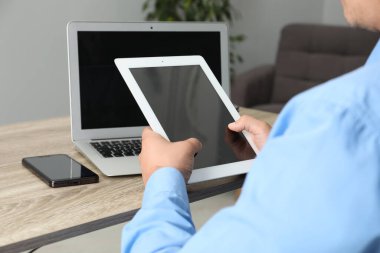 Tabletli, akıllı telefonlu ve bilgisayarlı bir iş adamı ahşap masada, yakın plan. Modern teknoloji