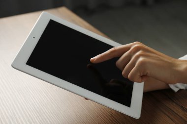 İş kadını, kapalı bir masada tablet kullanıyor, yakın plan. Modern teknoloji