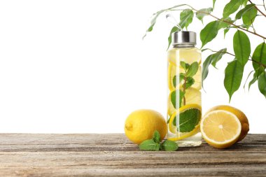 Şişe içinde naneli limon suyu ve beyaz arka planda tahta masada taze meyveler. Metin için boşluk