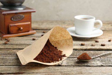 Kağıt filtre, öğütülmüş kahve, öğütücü ve bir bardak içki.