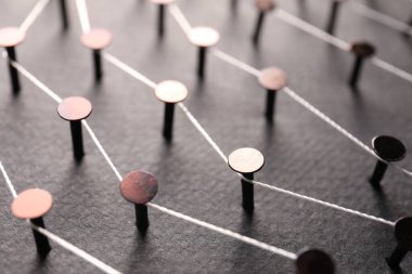 Ağ bağlantısı. Renk arkaplanındaki iplikle birbirine bağlanmış tırnaklar, yakın plan