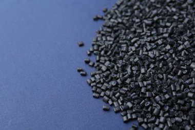 Mavi arka planda siyah plastik granüller yığını, yakın plan. Metin için boşluk