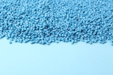 Açık mavi arka planda plastik granüller yığını, yakın plan. Metin için boşluk