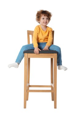 Küçük çocuk beyaz arka planda taburede oturuyor.