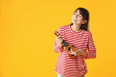 Turuncu arka planda ukulele çalan mutlu kadın, metin için boşluk