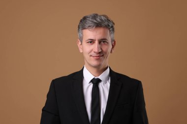 Kahverengi arka planda ceketli iş adamının portresi