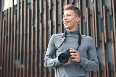 Açık havada duvarın yanında modern kamerası olan profesyonel bir fotoğrafçı. Metin için boşluk