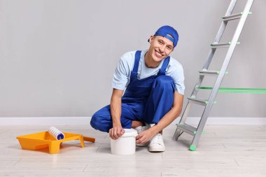 Gülümseyen tamirci duvarları içeride boyamaya hazırlanıyor.