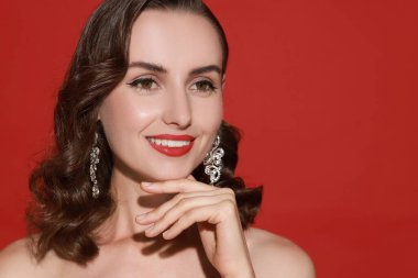 Kırmızı arka planda mükemmel makyajlı gülümseyen kadın. Metin için boşluk