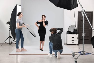 Profesyonel fotoğraf stüdyosunda modelle çalışan fotoğrafçı ve asistan.