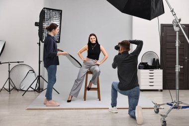 Profesyonel fotoğraf stüdyosunda modelle çalışan fotoğrafçı ve asistan.