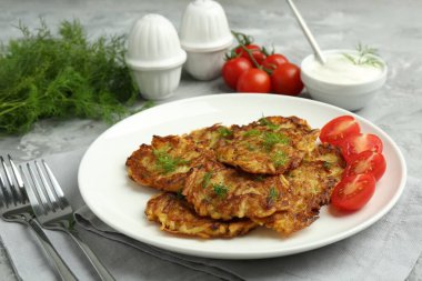 Gri masada servis edilen taze domatesli leziz patates krepleri.