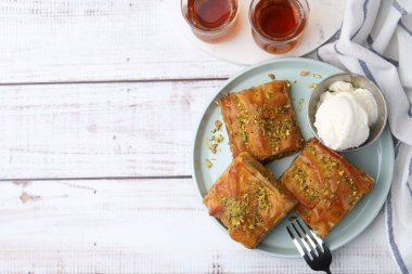 Hafif ahşap masada servis edilen ezilmiş fındıklı ve dondurmalı enfes baklava. Metin için boşluk