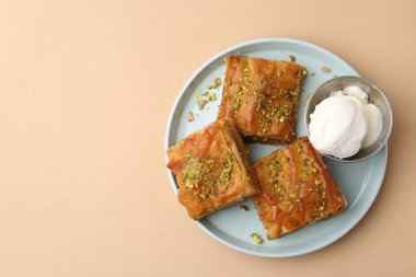 Ezilmiş fındıklı enfes baklava ve bej masa üzerinde dondurma, üst manzara. Metin için boşluk
