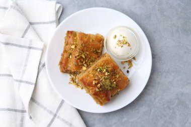 Lezzetli baklava, doğranmış fındık ve bir kepçe dondurma.