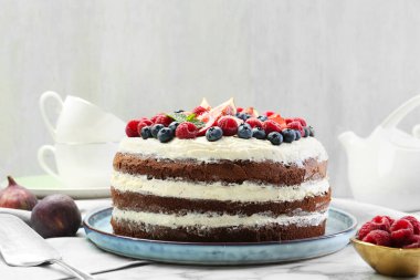 Lezzetli çikolatalı kek, beyaz masada servis edilen çilekli.