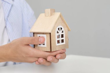 Emlak sigortası. Işık masasında ahşap ev figürlü bir adam, yakın plan. Metin için boşluk