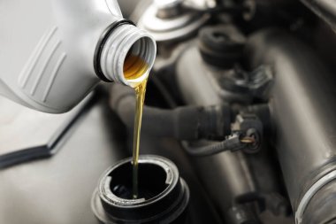Araba motoruna motor yağı dökülüyor, yakın plan.