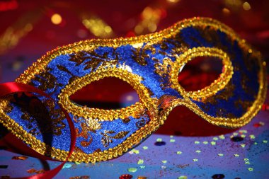 Renkli arka planda güzel bir karnaval maskesi, kurdele ve konfeti, yakın plan