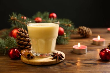Lezzetli Noel kokteyli (eggnog) cam, şenlikli dekor ve ahşap masada yanan mumlar, yakın plan
