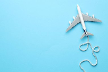 Plane model takes off and rope as condensation trail on light blue background, top view. Space for text clipart