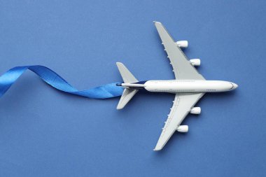 Plane model takes off and ribbon as condensation trail on blue background, top view clipart