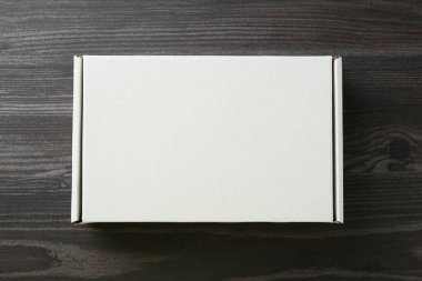 Ahşap arka planda boş bir karton kutu, üst manzara. Tasarım için model