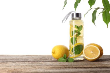 Şişe içinde naneli limon suyu ve beyaz arka planda tahta masada taze meyveler. Metin için boşluk