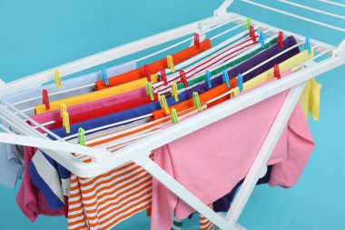 Açık mavi arka planda temiz çamaşırları olan kuru askı, yakın plan.