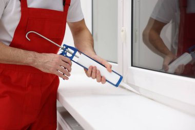 Caulking gun ile çalışan işçiler pencereyi içeriden kapatıyor.