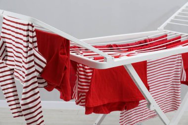 Gri duvarın yanında temiz çamaşırları olan kuru askı, yakın plan.